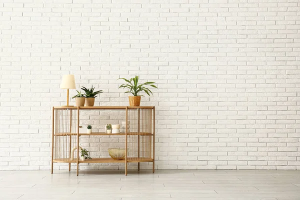 Meja Dengan Tanaman Rumah Dan Lampu Dekat Dinding Bata Putih — Stok Foto