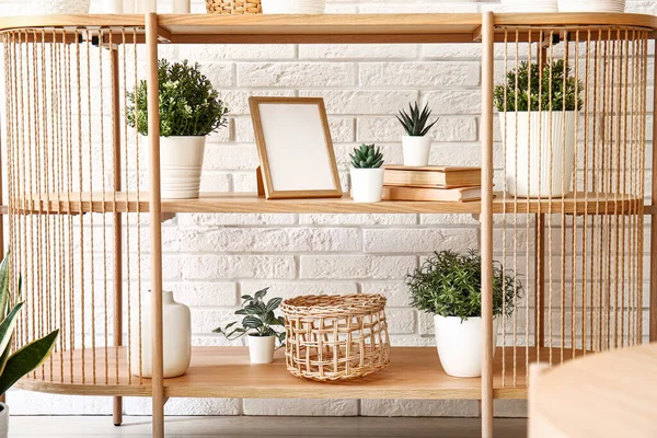 Tisch Mit Zimmerpflanzen Gestell Und Büchern Neben Weißer Ziegelwand — Stockfoto