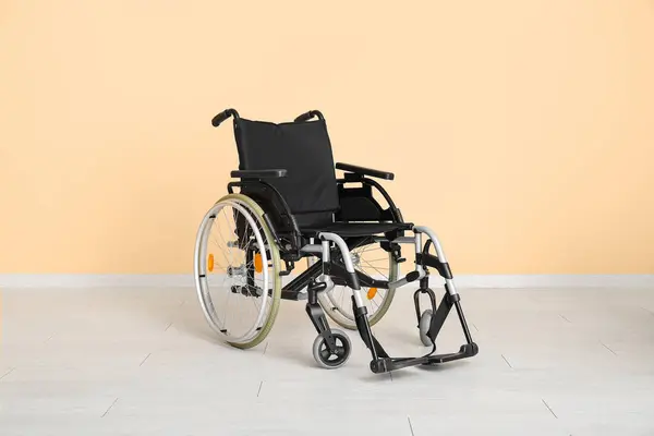 Пустое Инвалидное Кресло Возле Бежевой Стены — стоковое фото