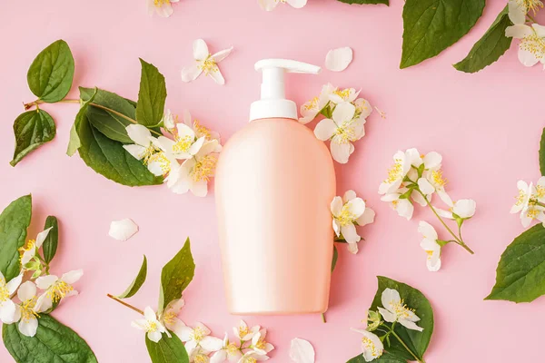 Zusammensetzung Mit Einer Flasche Kosmetikprodukt Und Jasminblüten Auf Rosa Hintergrund — Stockfoto