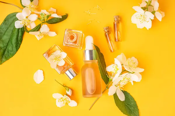 Composition with cosmetic products and beautiful jasmine flowers on color background
