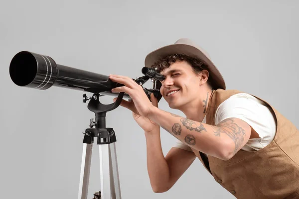 年轻人在灰蒙蒙的背景下通过望远镜看星星 — 图库照片