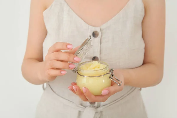 Woman with jar of lemon body scrub on white background