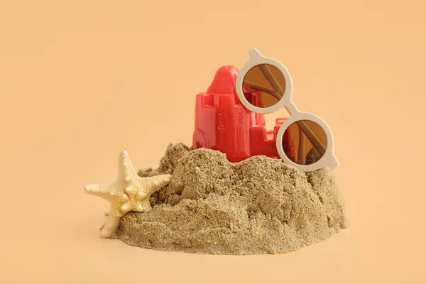 Замок Піску Пляжною Іграшкою Морськими Зірками Сонцезахисними Окулярами Помаранчевому Фоні — стокове фото
