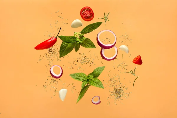 Flying spices and vegetables on color background