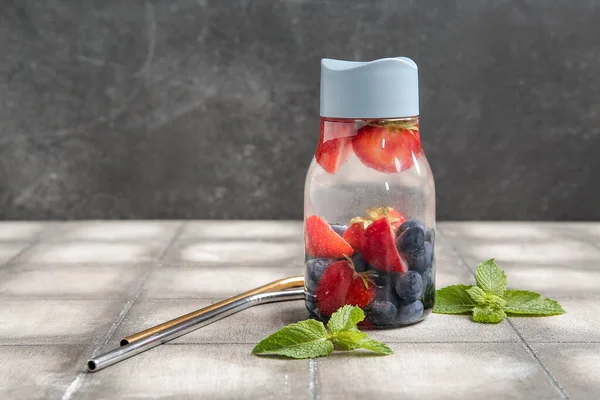 运动瓶装注入蓝莓 草莓和薄荷在灰色瓷砖桌上的水 — 图库照片