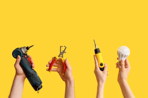Eletricista Mãos Com Lâmpada Ferramentas Fundo Amarelo — Fotografia de Stock