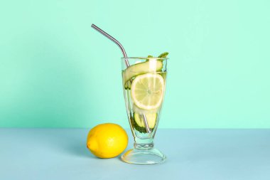Mavi arka planda bir bardak salatalıklı limonata ve nane şekeri.