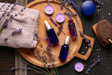 Kozmetik ürünleri, spa aksesuarları ve lavanta çiçekleri ile koyu arka planda kompozisyon