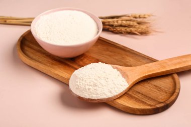 Pembe arka planda un olan kase ve kaşık, yakın plan.