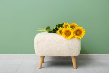 Yeşil duvarın yanında güzel ayçiçekleri olan bankta.