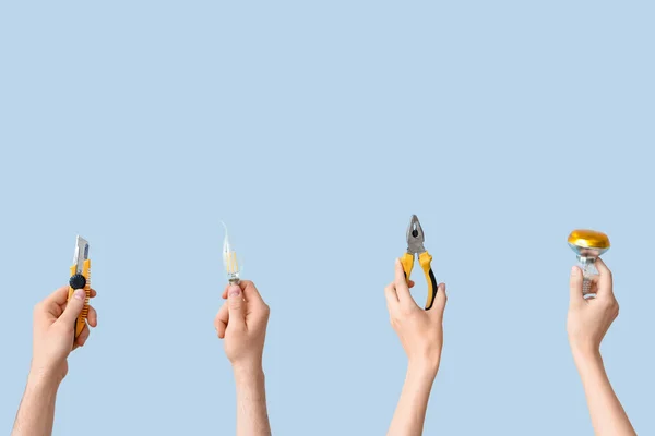 電球と灰色の背景のツールで電気技師の手 — ストック写真