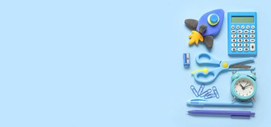 Plastikten yapılmış roket, alarm saati ve açık mavi zemin üzerinde metin için boşluk olan kırtasiye malzemesi