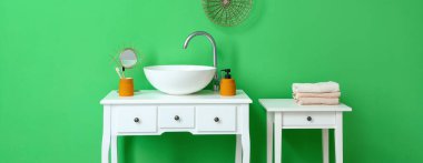 Beyaz masaları, lavabosu ve havluları olan şık bir banyo.