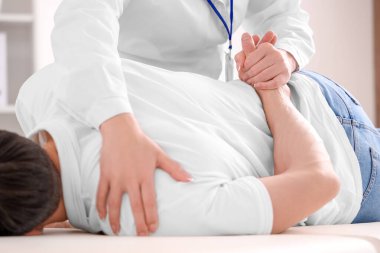 Rehabilitasyon merkezinde genç bir adamla çalışan kadın fizyoterapist.
