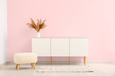 Pampa otlu modern çekmeceler ve odada pembe duvarın yanında bank.