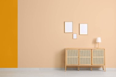 İçinde lamba olan modern çekmeceler ve odadaki bej duvarda asılı boş resimler