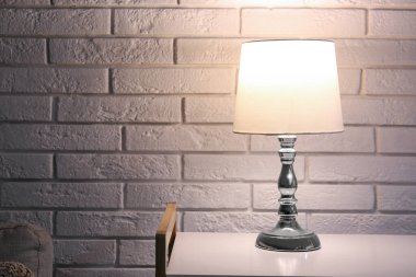 Karanlık odada beyaz tuğla duvarın yanındaki raflarda parlayan lamba.