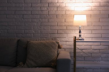 Gri kanepenin yanındaki raflarda parlayan lamba.