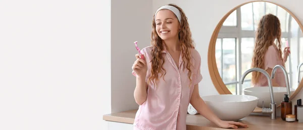 Young woman in pajamas and with razor in bathroom