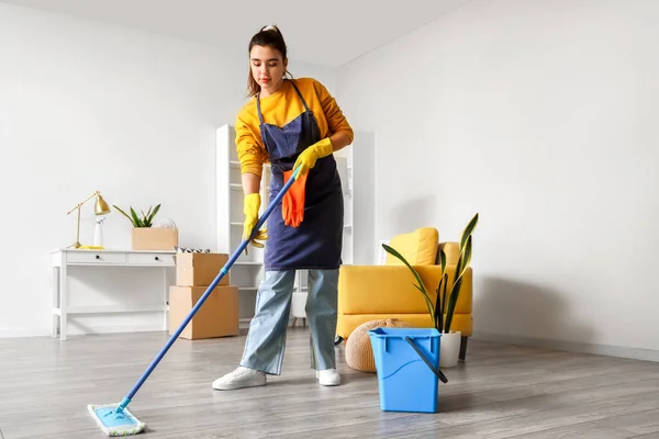年轻妇女在家里扫地 — 图库照片