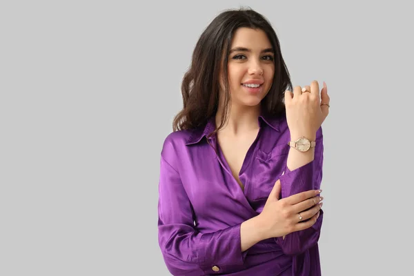 灰色の背景に腕時計を持つエレガントな美しい若い女性 — ストック写真