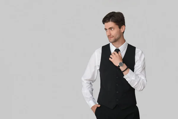 灰色の背景に腕時計を持つハンサムな若いビジネスマン — ストック写真