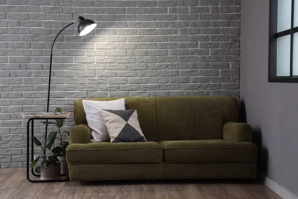 Glowing Lamp Cozy Green Sofa Grey Brick Wall — Stock Photo, Image