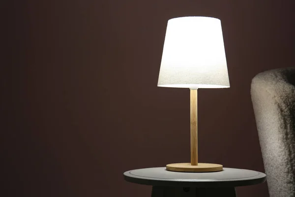 暗い部屋のソファーの近くの木のテーブルの光るランプ — ストック写真
