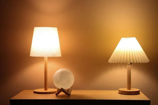 Different Glowing Lamps Wooden Table Dark Room — Stock Photo, Image