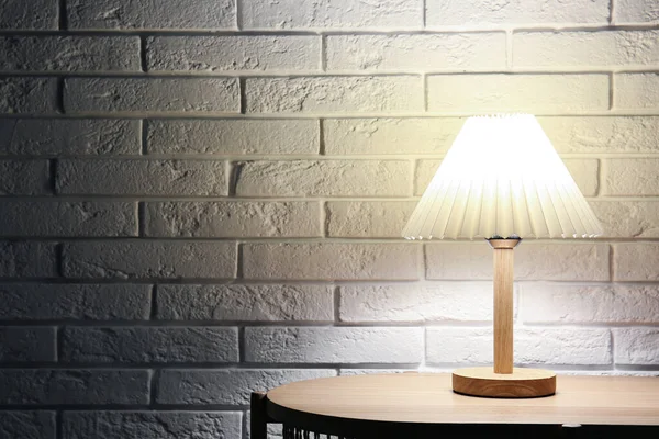 Светящаяся Лампа Деревянном Столе Возле Белой Кирпичной Стены Темной Комнате — стоковое фото