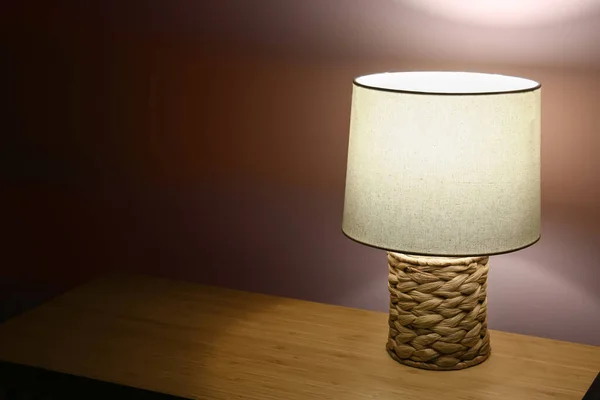 Koyu Renkli Odada Bej Duvarın Yanındaki Ahşap Masada Parlayan Lamba — Stok fotoğraf