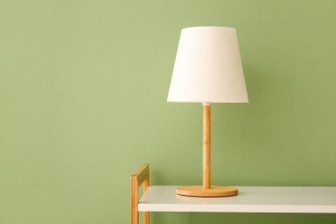 Masa lambası yeşil duvarın yanındaki beyaz rafta.