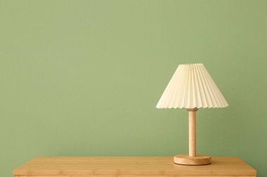 Lamba, yeşil duvarın yanındaki ahşap masada.