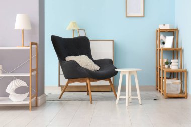 Gri kanepeli, raf üniteli ve taburesi olan oturma odasının içinde.