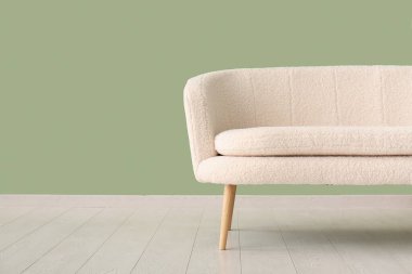 Yeşil duvarın yanındaki beyaz kanepe, yakın plan.