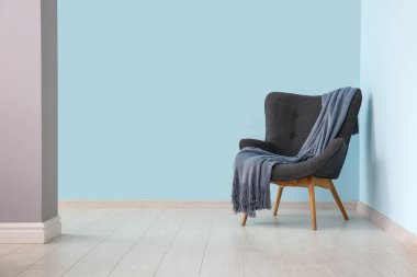 Mavi duvarın yanında battaniyeli gri koltuk