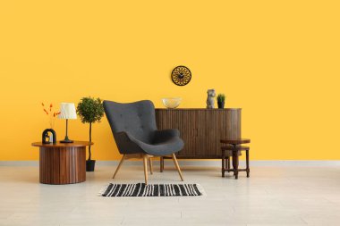 Gri koltuğu, sehpası ve ahşap dolabı olan oturma odasının içinde.