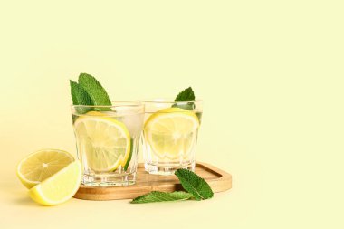 Arkaplanda soğuk mojito, limon ve nane içeren ahşap bir tahta.