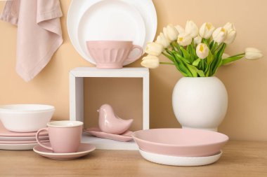 Ahşap tezgahta lale çiçekli temiz tabak ve vazo takımı.