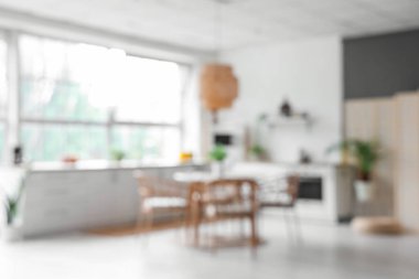 Beyaz tezgahlı, yemek masalı ve büyük pencereli aydınlık mutfağın içi bulanık görünüyor.