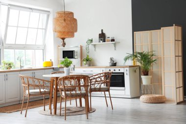 Beyaz tezgahlı, yemek masalı ve büyük pencereli aydınlık mutfağın içi.