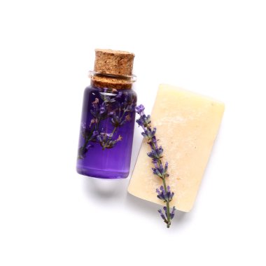 Beyaz arka planda bir şişe lavanta yağı ve sabun.