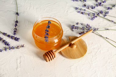 Beyaz masadaki tatlı lavanta kavanozu, bal ve çiçek.