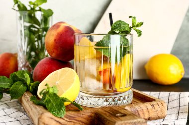 Bir bardak taze şeftalili limonata ve siyah masada nane şekeri.