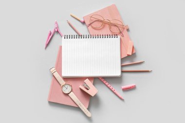 Boş defter, gözlük, kol saati ve beyaz arkaplanda farklı okul sayfası olan kompozisyon