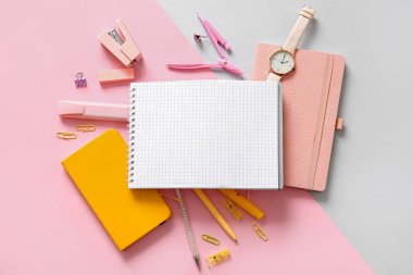 Renk arkaplanı üzerinde boş defter, kol saati ve farklı okul kırtasiyesi olan kompozisyon