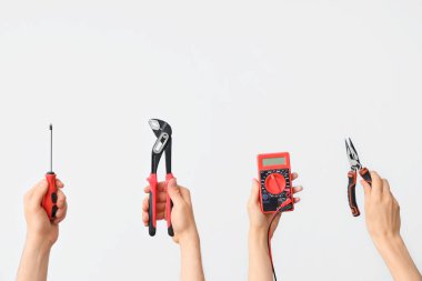 Electrician hands with tools on grey background