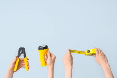 Electrician hands with tools on grey background