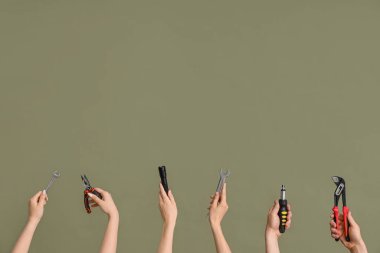 Electrician hands with tools on green background